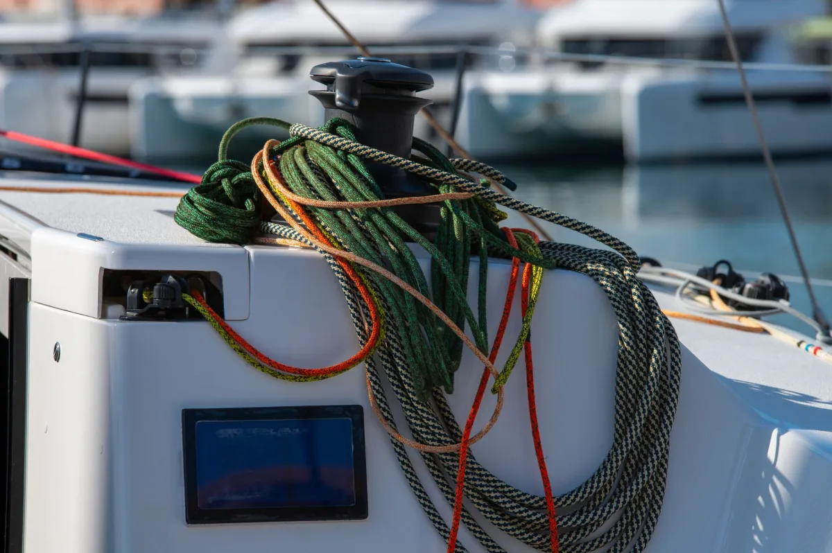 Detailed view of colorful nautical ropes and winch on a sailboat in a sunny marina.