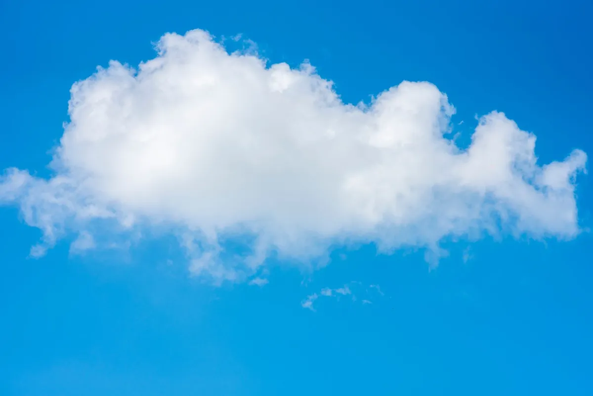 Single fluffy cloud in a clear blue sky, showcasing serene weather.