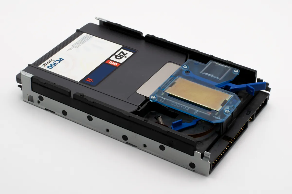 Close-up of a vintage PC100 Zip disk drive, highlighting its retro design and data storage function.