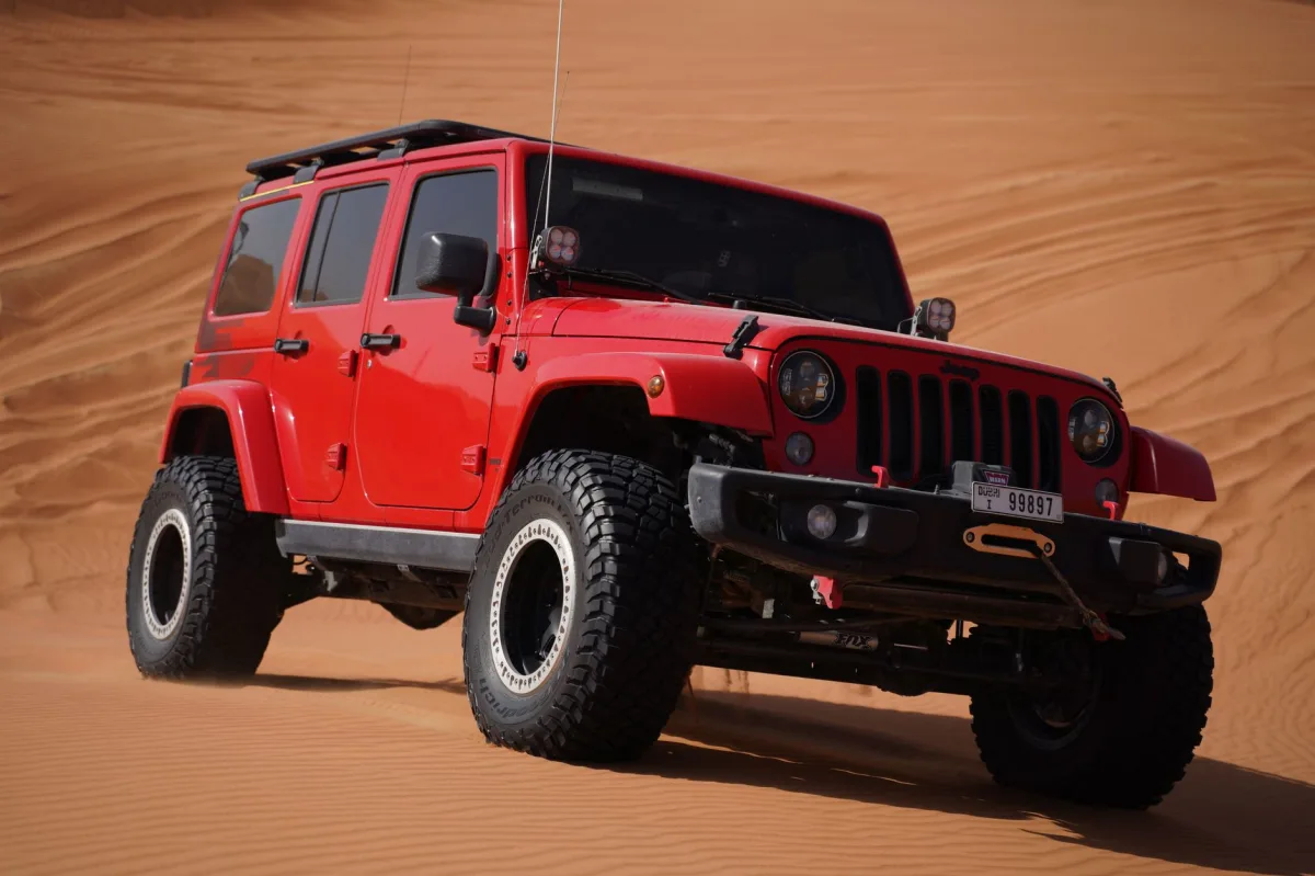 Jeep Wrangler on a rocky trail with dust kicking up.