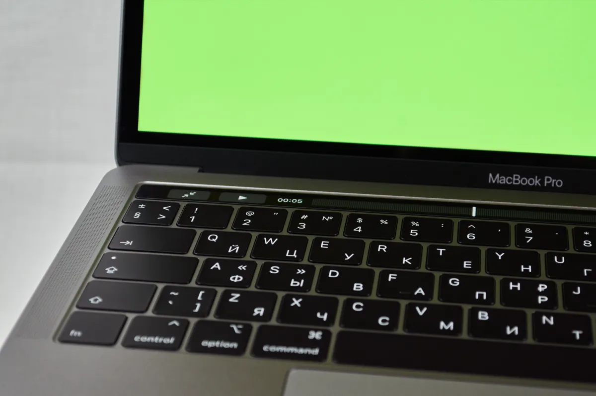 Russian keyboard MacBook Pro with a green screen. Modern electronic device.